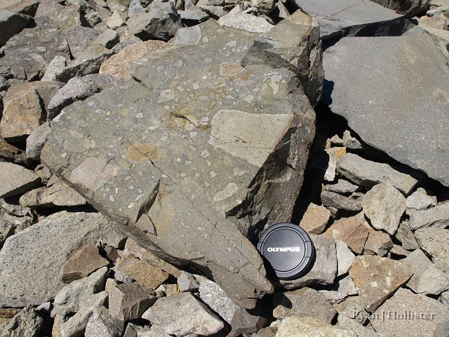 _7264408.JPG - Some really neat clasts surrounded by what must be a thick ashflow or mudflow.  Lens cap is 70mm for scale.