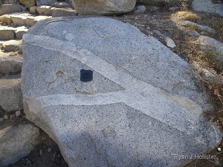 _9235186.JPG - A cool little feldspar-rich vein cutting across the granite.  My lens cap is about 3.5 inches for scale.  SO what do you think?  Did the intrusion start in two branches and merge into one, or did it branch off from right to left?