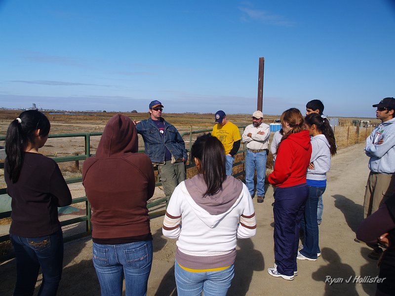 mendota_wildLink_111409_0911.JPG - Jason Dean, the Meyers Farm biologist explains how his boss' farm pumps water out of the Fresno Slough in wet years and into their holding ponds behind the students.  Hydrostatic pressure then forces the water down into the aquifer for storage.