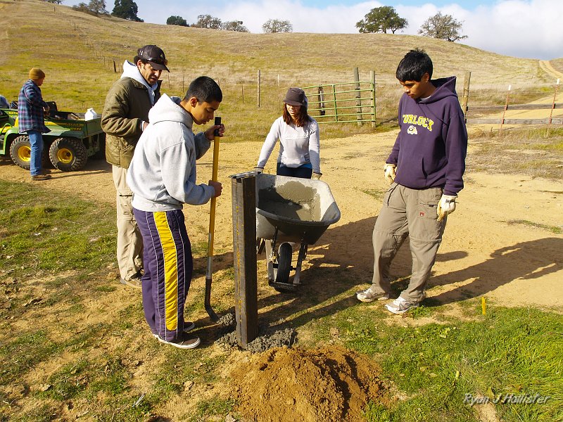 pacheco_120509_1043.JPG - Once the post was set, the students had to level it, then tamped the concrete into place.